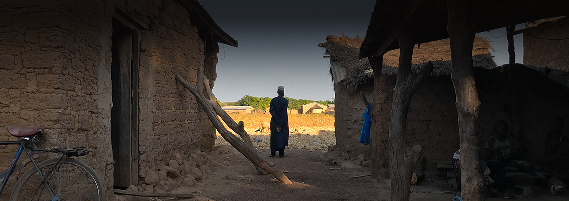 Man standing next to home in West African village